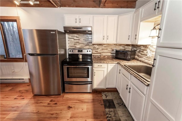 kitchen featuring under cabinet range hood, baseboard heating, stainless steel appliances, white cabinetry, and a sink