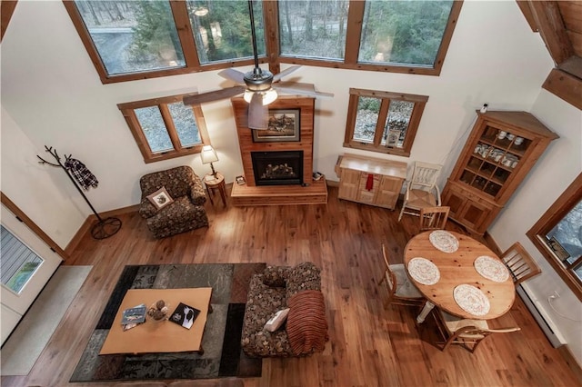 living area featuring a baseboard heating unit, wood finished floors, and a fireplace