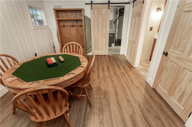 dining room with a barn door, visible vents, and light wood finished floors