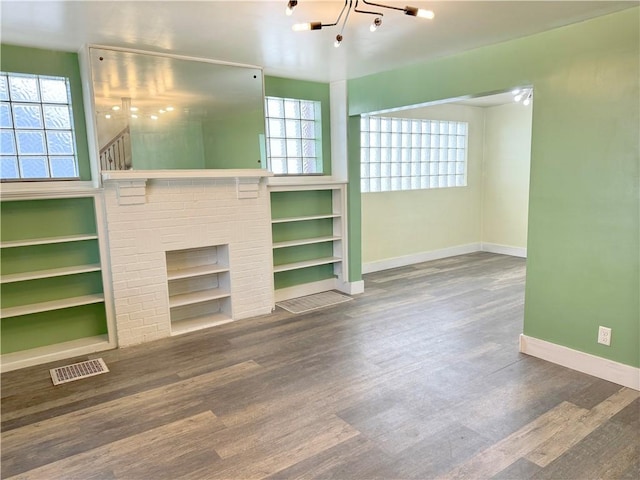 unfurnished living room featuring visible vents, a brick fireplace, baseboards, and wood finished floors