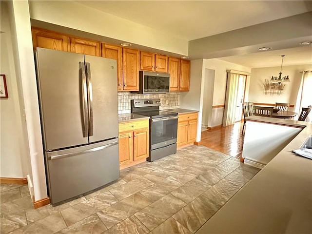 kitchen with decorative backsplash, decorative light fixtures, baseboards, and appliances with stainless steel finishes