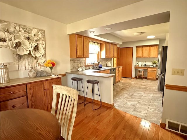 kitchen featuring visible vents, a peninsula, stainless steel appliances, a sink, and tasteful backsplash