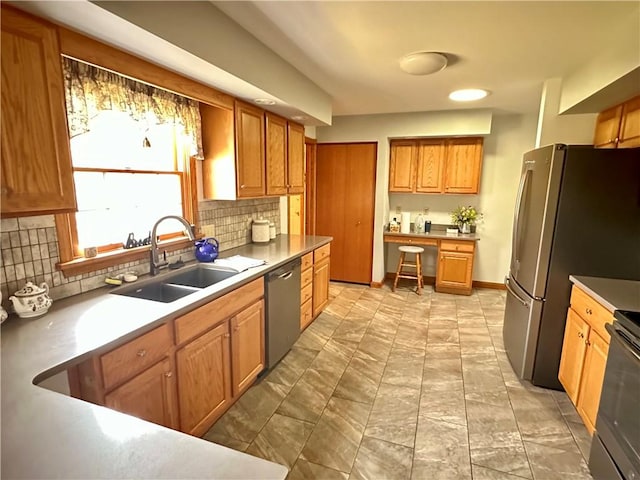 kitchen with backsplash, baseboards, brown cabinets, appliances with stainless steel finishes, and a sink