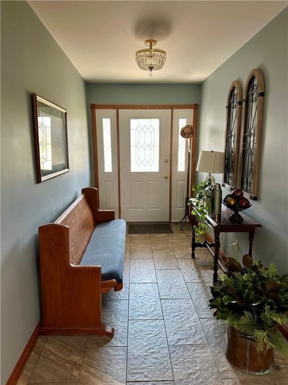 entryway featuring a wealth of natural light, stone tile floors, and baseboards