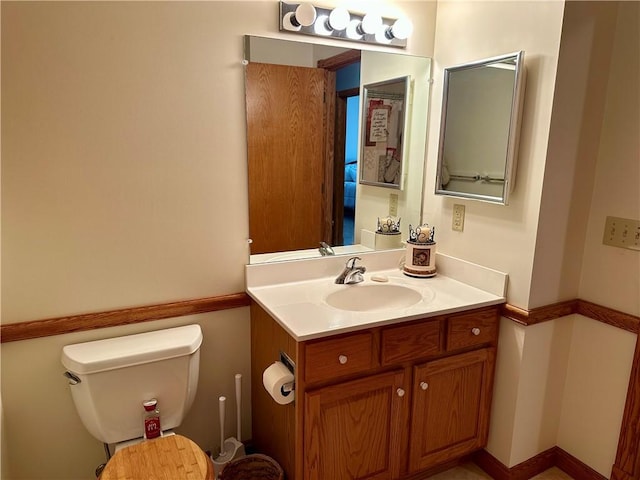 bathroom with baseboards, toilet, and vanity