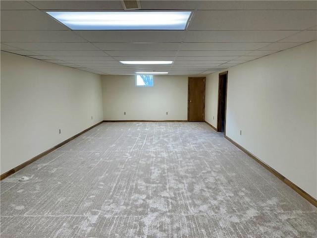 below grade area featuring carpet flooring, baseboards, and a drop ceiling