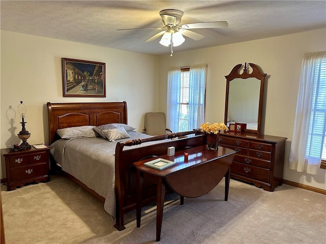 bedroom with light colored carpet, a textured ceiling, baseboards, and ceiling fan