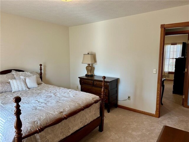 bedroom featuring baseboards, light colored carpet, and a textured ceiling