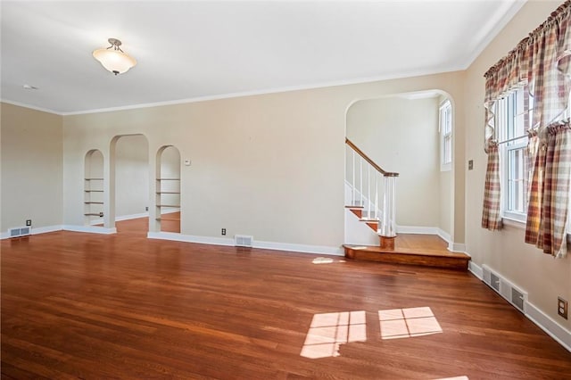 spare room featuring visible vents, arched walkways, wood finished floors, and stairs