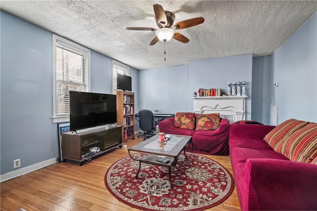 living room with light wood-type flooring, baseboards, a textured ceiling, and a ceiling fan