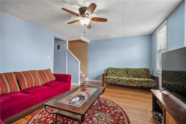 living room with visible vents, a ceiling fan, a textured ceiling, wood finished floors, and stairs