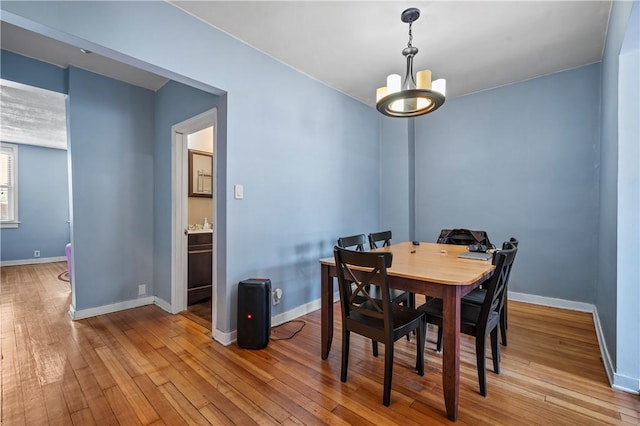 dining area with a notable chandelier, baseboards, and hardwood / wood-style flooring