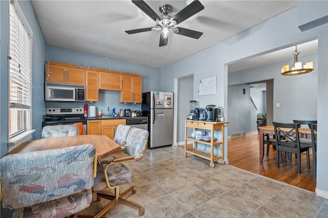 kitchen with ceiling fan with notable chandelier, a sink, dark countertops, appliances with stainless steel finishes, and baseboards