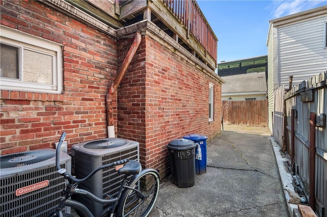 exterior space featuring a patio area, fence, central AC unit, and brick siding