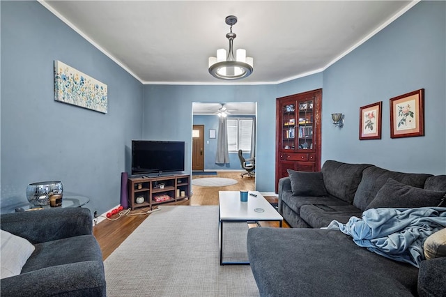 living room featuring baseboards, ceiling fan with notable chandelier, wood finished floors, and ornamental molding