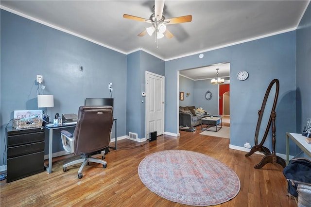 office area featuring baseboards, ceiling fan, ornamental molding, wood finished floors, and arched walkways