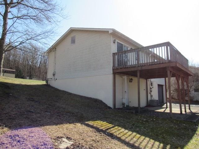 view of home's exterior featuring a wooden deck, a lawn, and a patio area