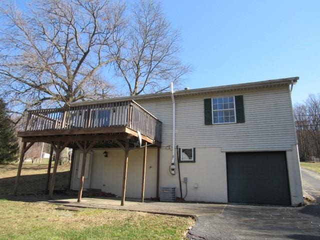 back of property featuring driveway, a deck, and an attached garage