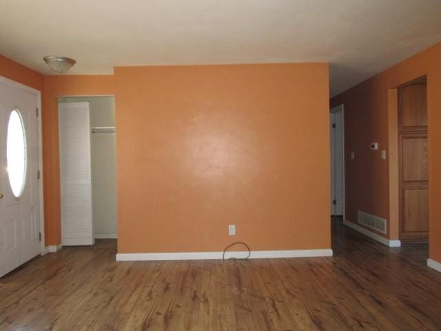 foyer entrance featuring wood finished floors, visible vents, and baseboards