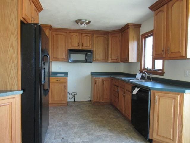 kitchen with black appliances, dark countertops, brown cabinetry, and a sink