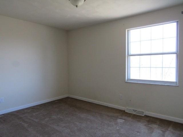 carpeted empty room with visible vents and baseboards