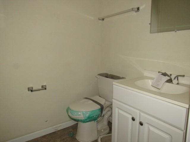 bathroom with toilet, vanity, and baseboards