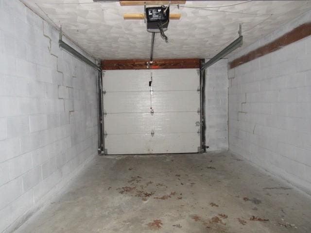 garage featuring concrete block wall and a garage door opener