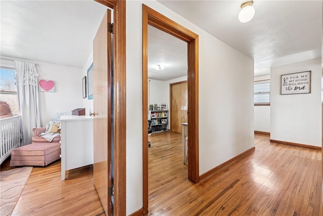 hall featuring light wood-type flooring and baseboards