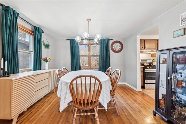 dining room with a wealth of natural light, a notable chandelier, and light wood-style floors