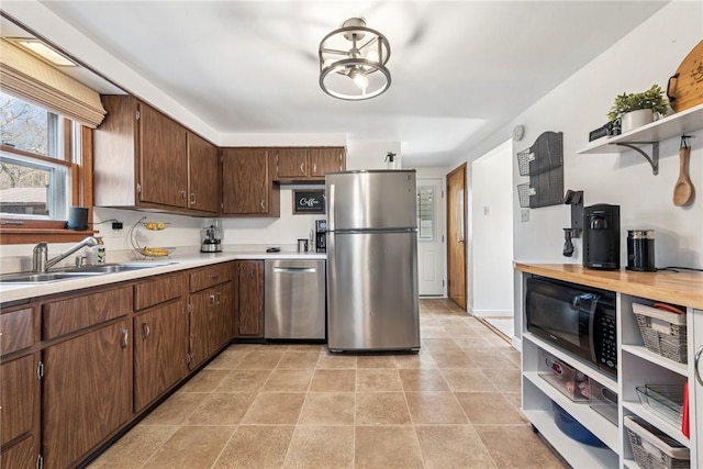 kitchen featuring a sink, stainless steel appliances, open shelves, and light countertops