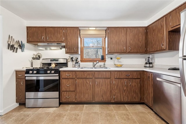 kitchen with under cabinet range hood, stainless steel appliances, light countertops, and a sink