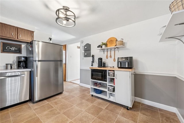 kitchen with stainless steel appliances, light countertops, baseboards, and open shelves