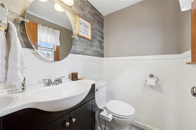 bathroom featuring vanity, toilet, and wainscoting