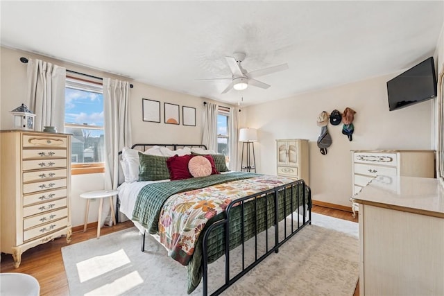 bedroom featuring multiple windows, light wood-type flooring, and baseboards