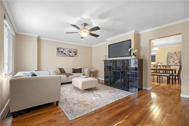 living room with baseboards, wood-type flooring, a fireplace, and crown molding