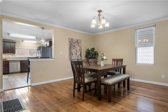 dining room featuring baseboards, crown molding, and light wood-style floors