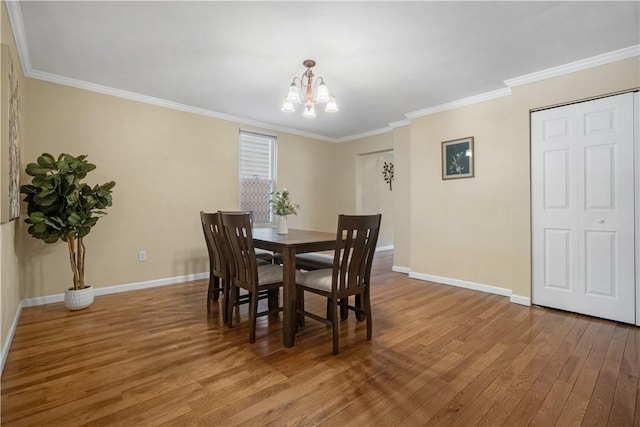 dining room featuring a notable chandelier, wood finished floors, baseboards, and ornamental molding