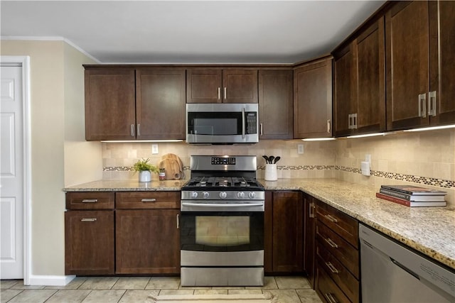 kitchen with dark brown cabinetry, appliances with stainless steel finishes, and light stone countertops