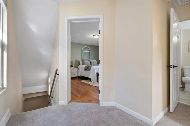 hallway featuring an upstairs landing, baseboards, and carpet floors