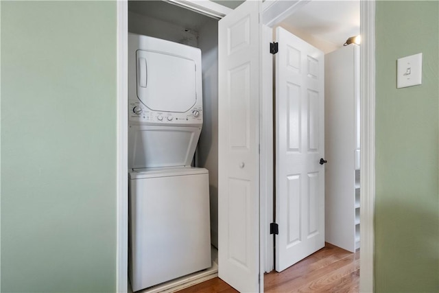 laundry room with laundry area, stacked washing maching and dryer, and light wood-type flooring