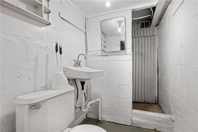 half bath featuring concrete block wall and toilet