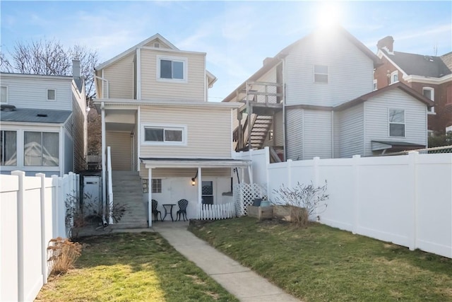 view of front of property with a front yard, a fenced backyard, and stairs