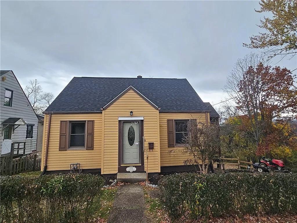 bungalow-style home featuring roof with shingles and fence