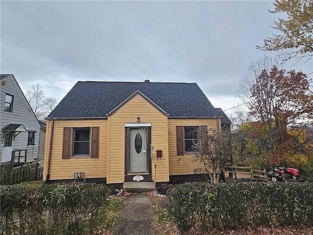 bungalow-style home featuring roof with shingles and fence