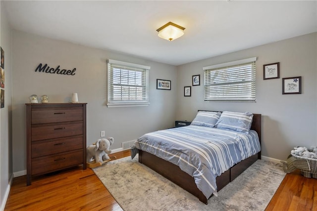 bedroom featuring visible vents, baseboards, and wood finished floors