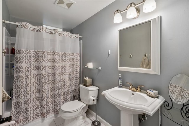 bathroom featuring toilet, a sink, curtained shower, tile patterned flooring, and baseboards