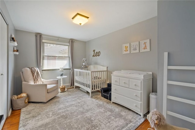 bedroom featuring a nursery area, wood finished floors, and baseboards