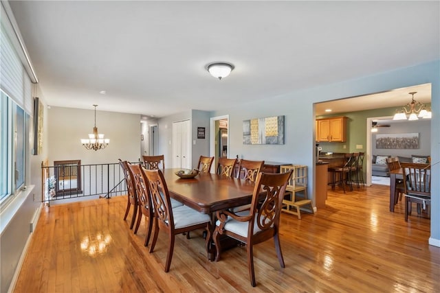 dining space with light wood-style floors and ceiling fan with notable chandelier