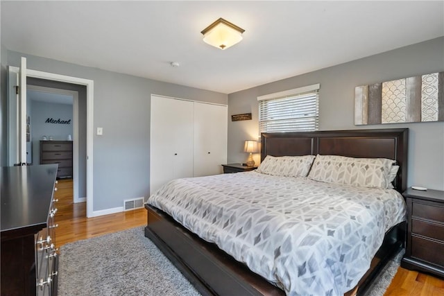 bedroom featuring visible vents, baseboards, a closet, and wood finished floors