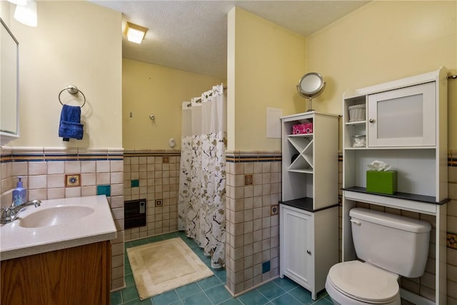 bathroom with tile patterned floors, a wainscoted wall, toilet, a textured ceiling, and tile walls